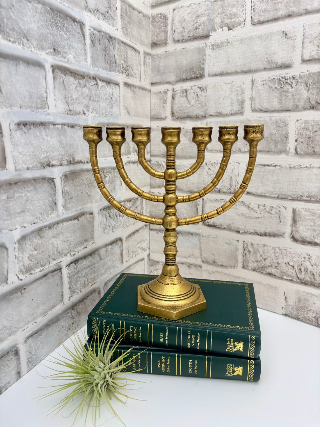 Brass Menorah on stacked books with a white brick wall background
