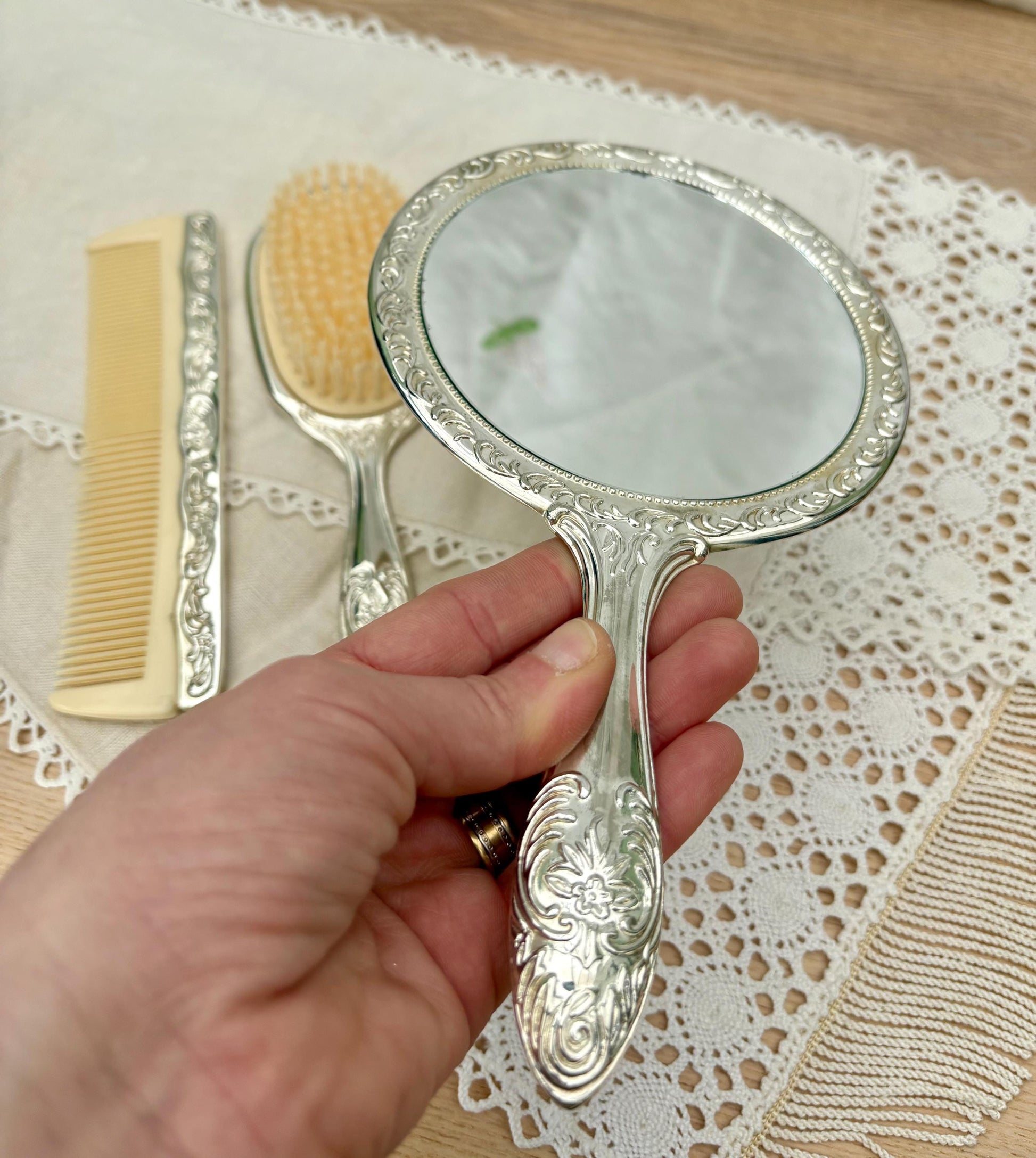 Vintage silver plated vanity set including a mirror, brush, and comb with intricate designs