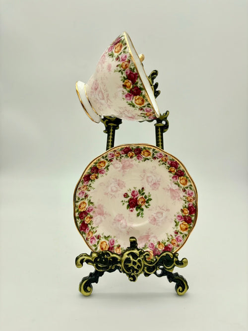 Decorative teacup and saucer set with floral patterns on a stand against a light background