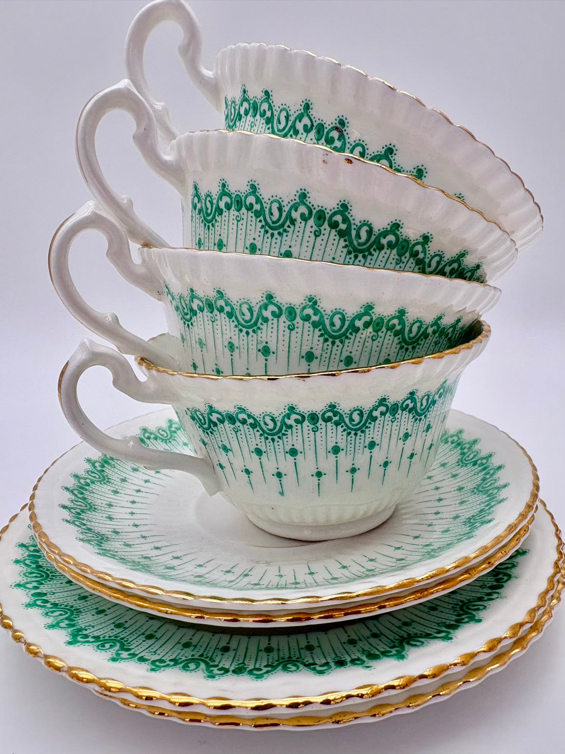 Stack of green and white teacups and saucers on a white background