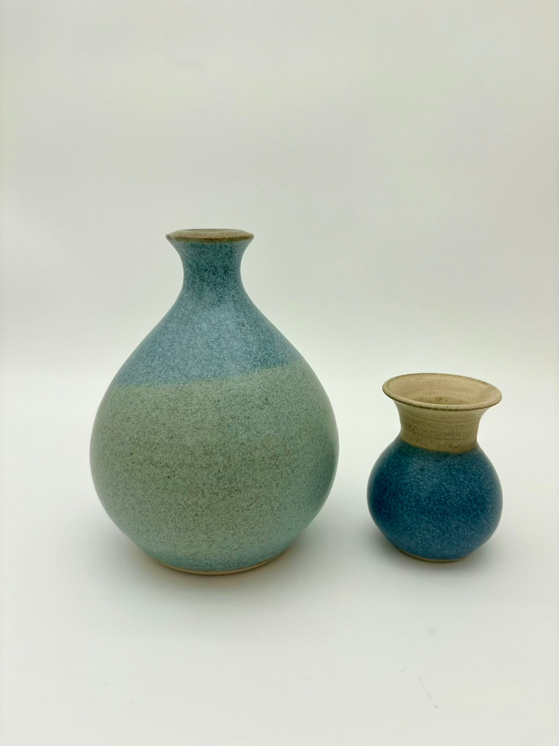 Two ceramic vases with a gradient blue and green finish on a white background