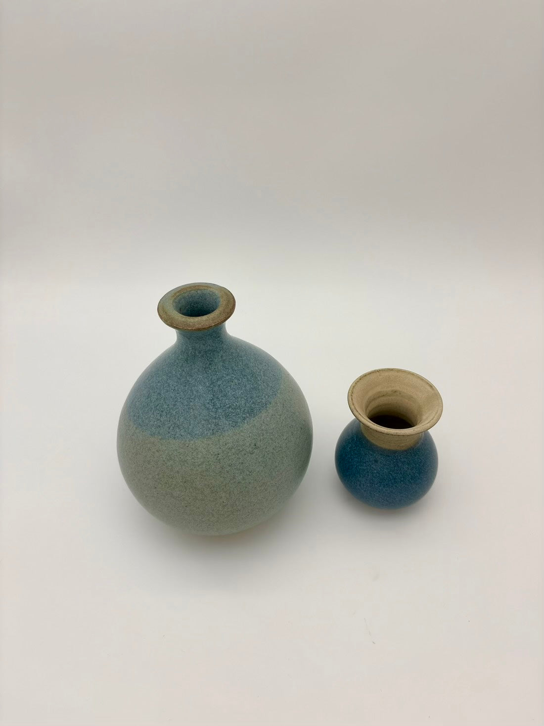 Two ceramic vases with a gradient blue and beige color on a white background