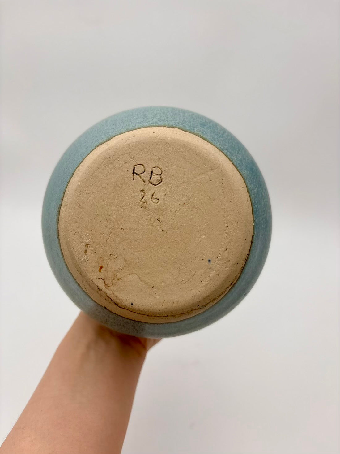 Ceramic bowl with 'RB 26' marking held by a hand against a white background