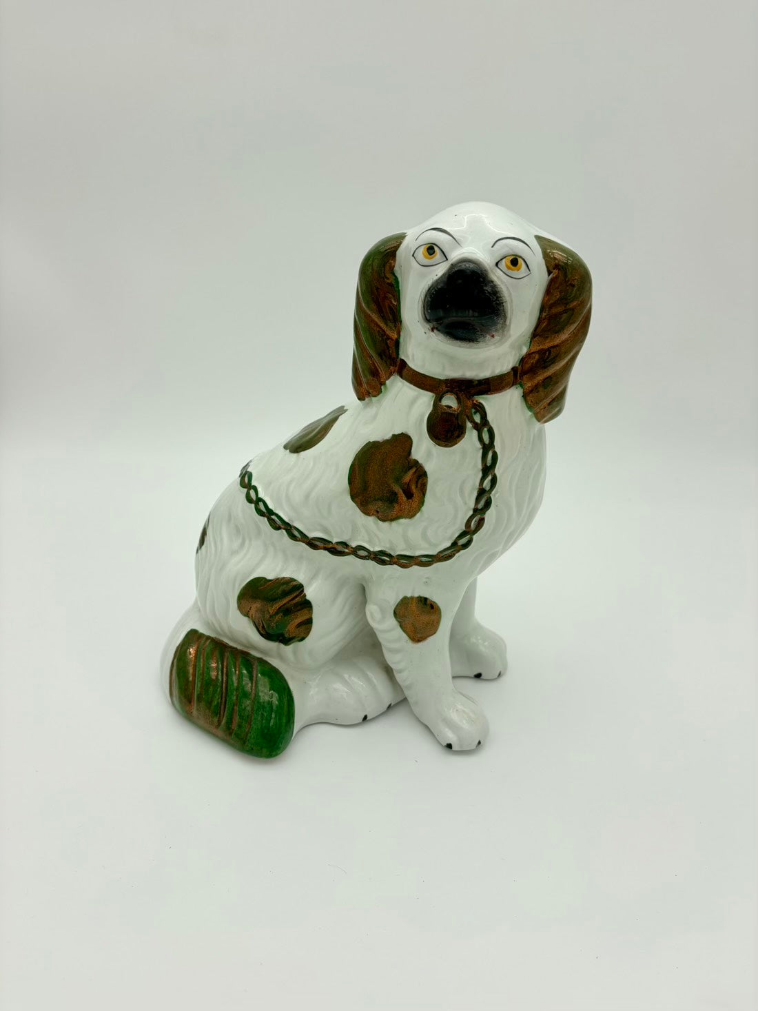 Ceramic dog figurine with a chain collar on a white background
