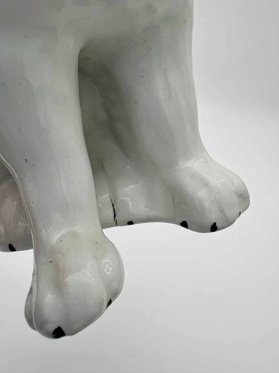Close-up of a white ceramic sculpture with black accents on a plain background