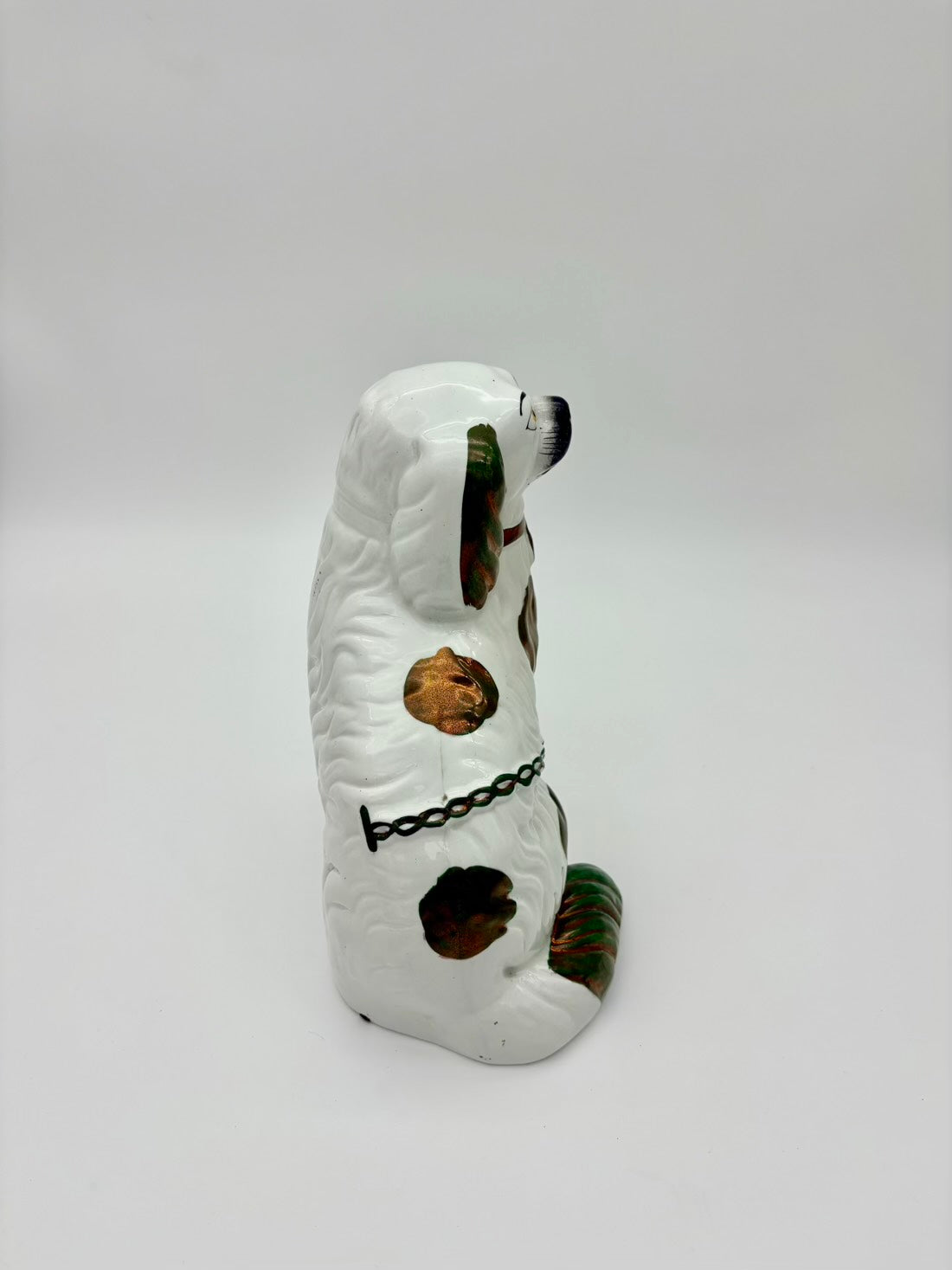 White ceramic dog figurine with black accents on a white background