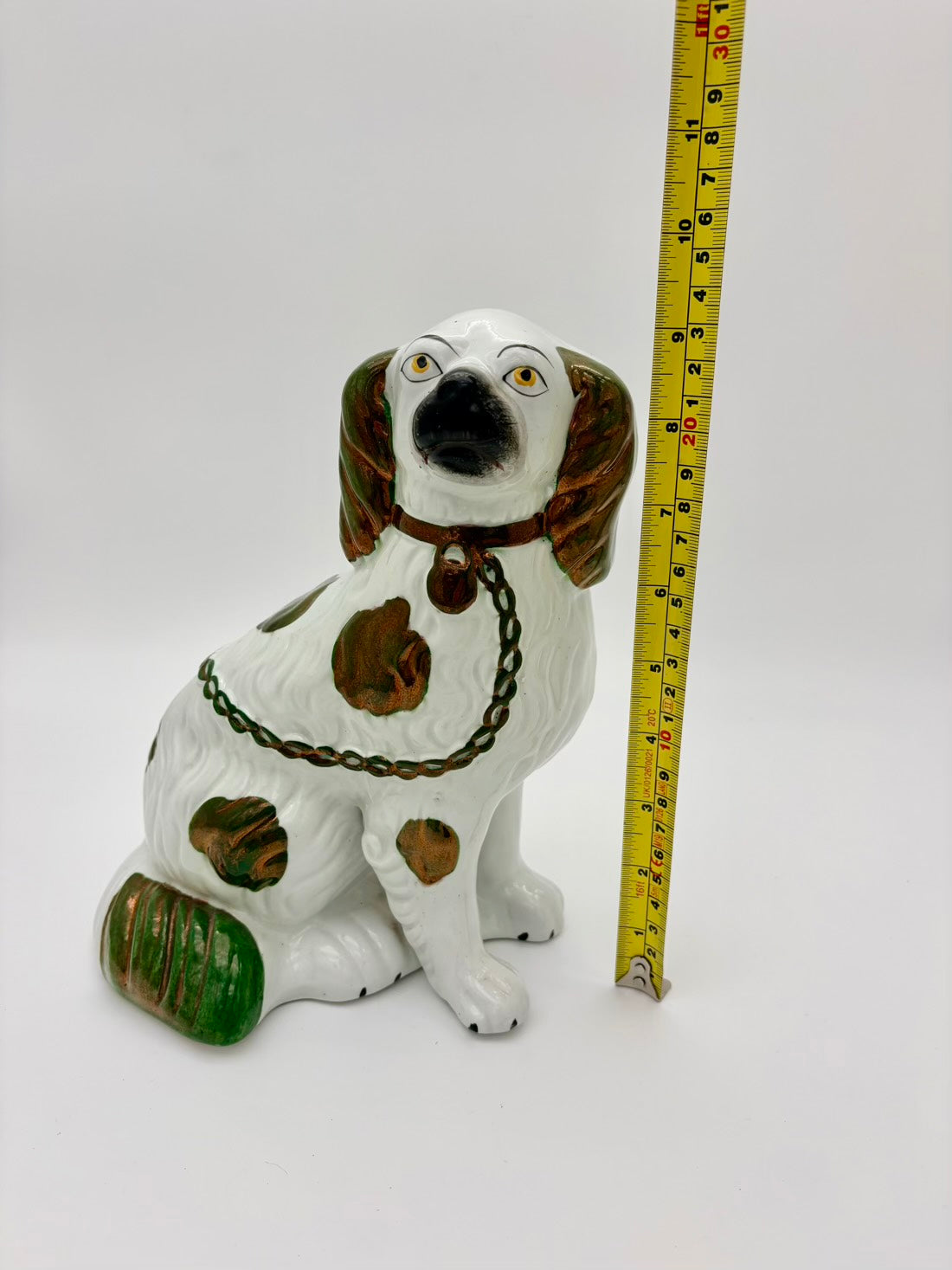 Decorative dog figurine with a measuring tape for scale on a white background