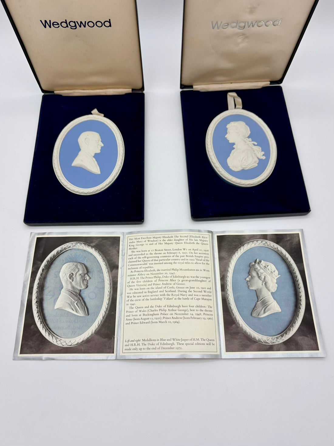 Two Wedgwood cameo brooches in open boxes with a display card showing more brooches.