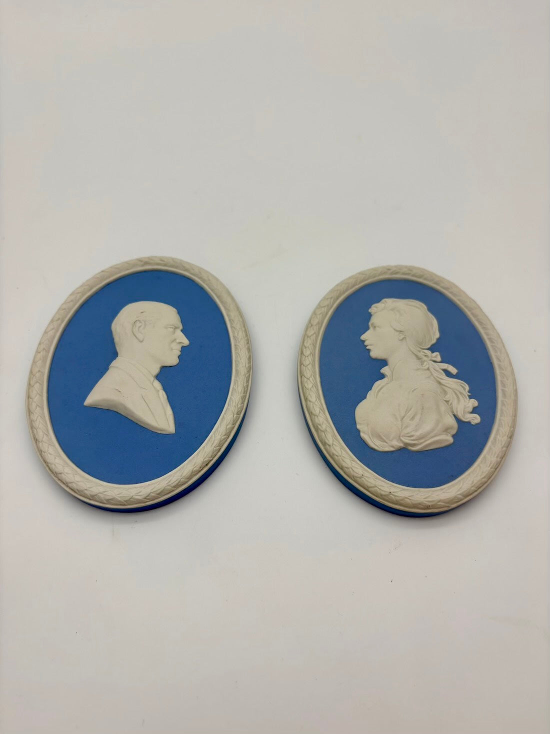 Two oval plaques with classical profiles on a white background