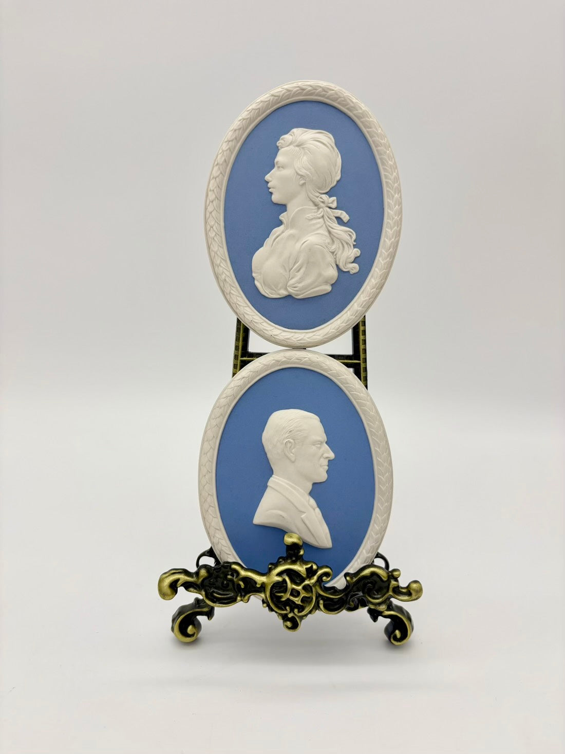 Two classical portrait medallions on a stand with a plain background