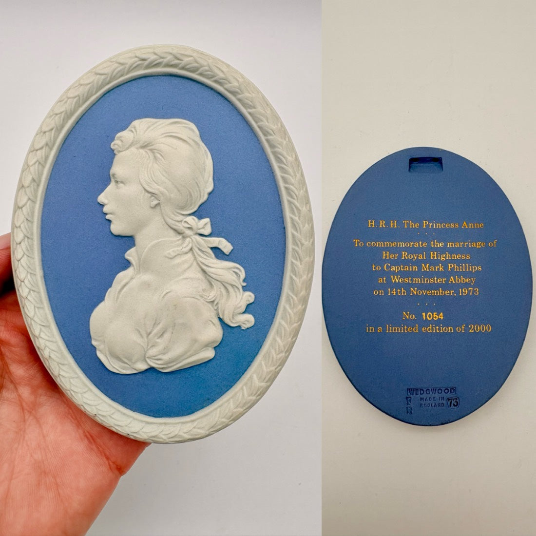 Wedgeback plaque with a portrait of a woman on a blue background, held by a hand.